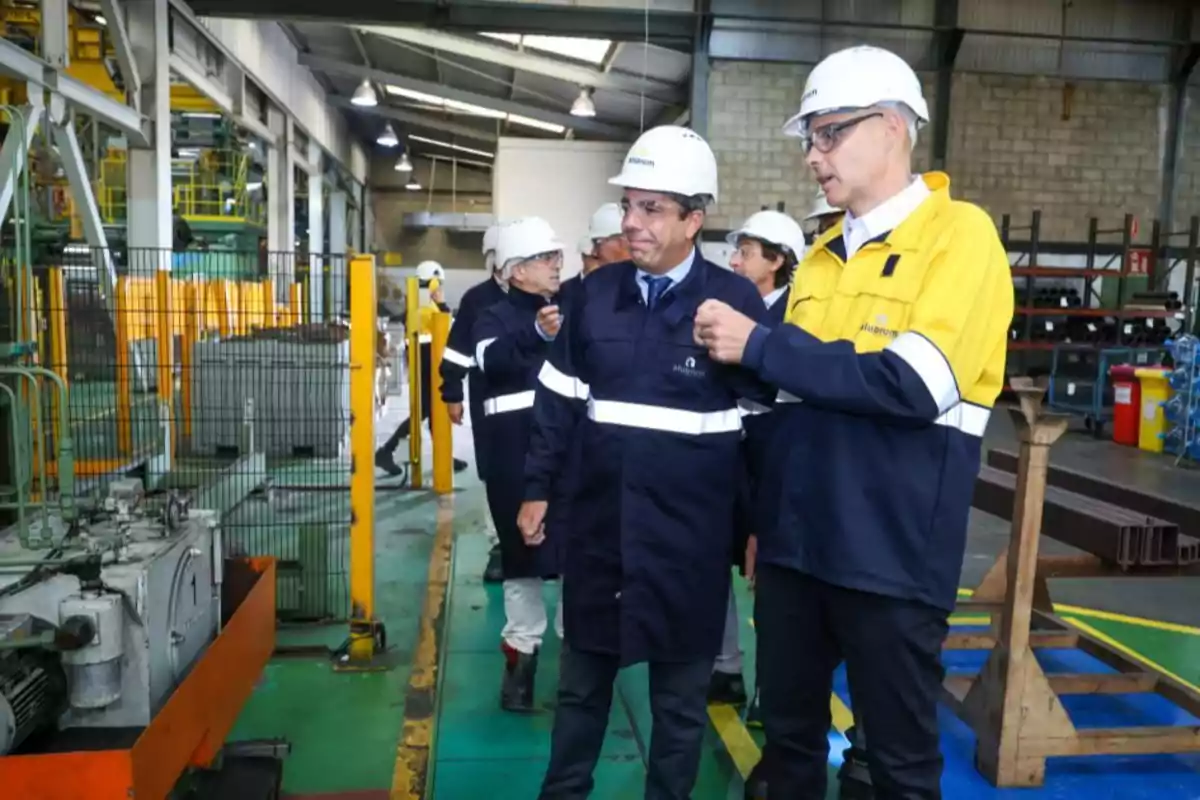 Grupo de personas con cascos y ropa de seguridad recorriendo una fábrica industrial