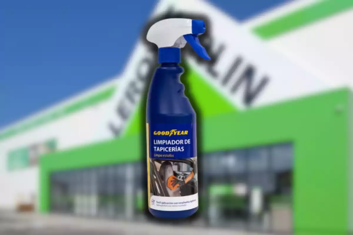Botella de limpiador de tapicerías Goodyear frente a una tienda con fachada verde y blanca desenfocada