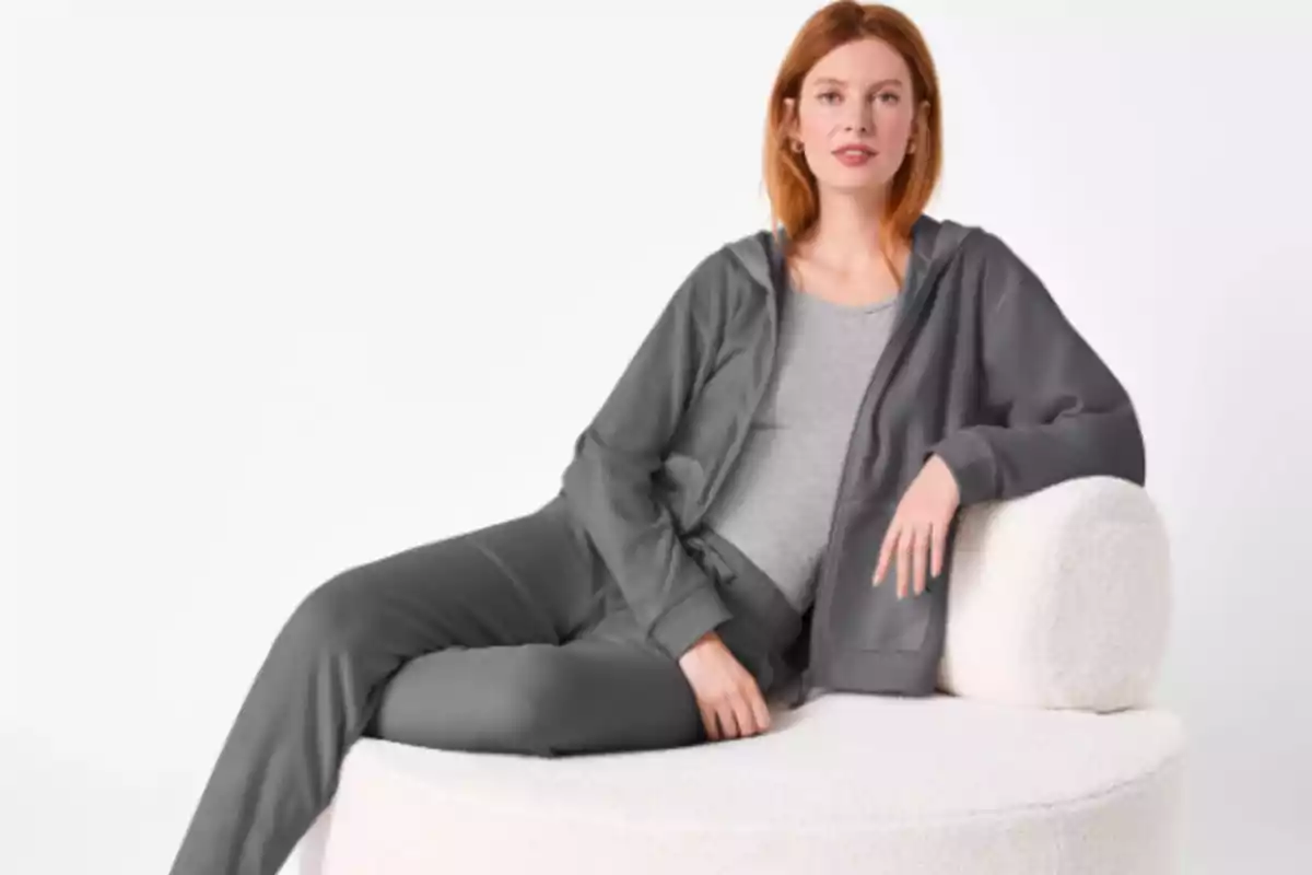 Mujer sentada en un sillón blanco usando ropa cómoda de color gris
