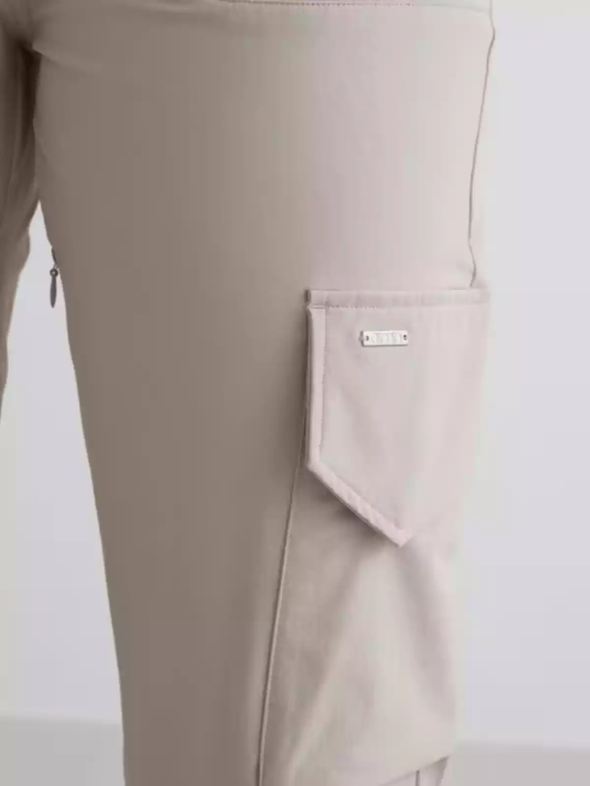 Pantalón beige con bolsillo lateral de solapa y detalle metálico decorativo