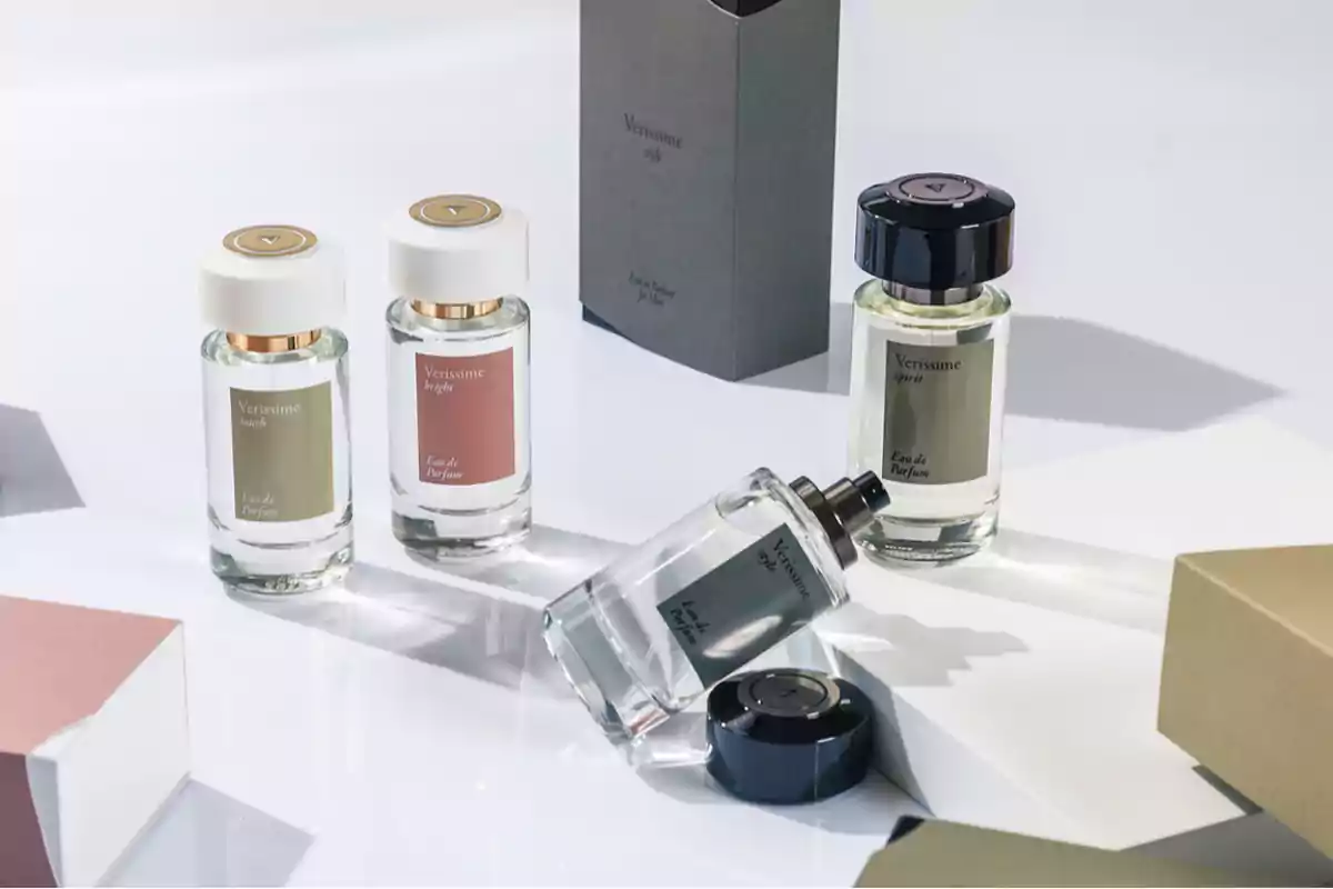 Frascos de perfume Verissime en diferentes presentaciones y colores sobre una superficie blanca junto a cajas de empaque elegantes Frascos de perfume Verissime en diferentes presentaciones y colores sobre una superficie blanca junto a cajas de empaque elegantes