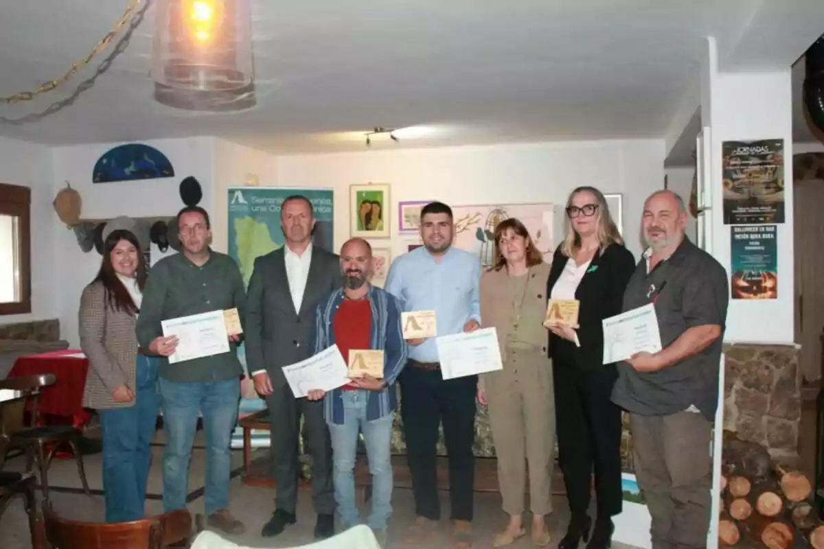 Grupo de personas posando en un interior mientras sostienen diplomas y placas de reconocimiento Grupo de personas posando en un interior mientras sostienen diplomas y placas de reconocimiento