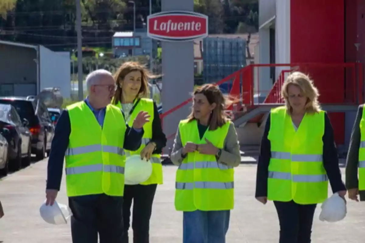 Varias personas con chalecos reflectantes caminan y conversan en el exterior de una fábrica con el letrero Lafuente visible al fondo