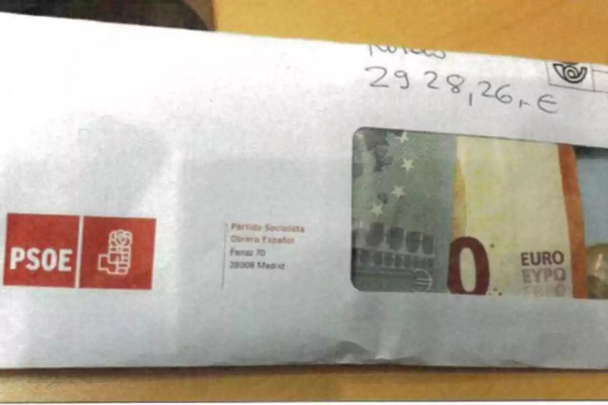 Sobre blanco con el logotipo del PSOE y una dirección en Madrid, que contiene un billete de cero euros visible a través de una ventana transparente