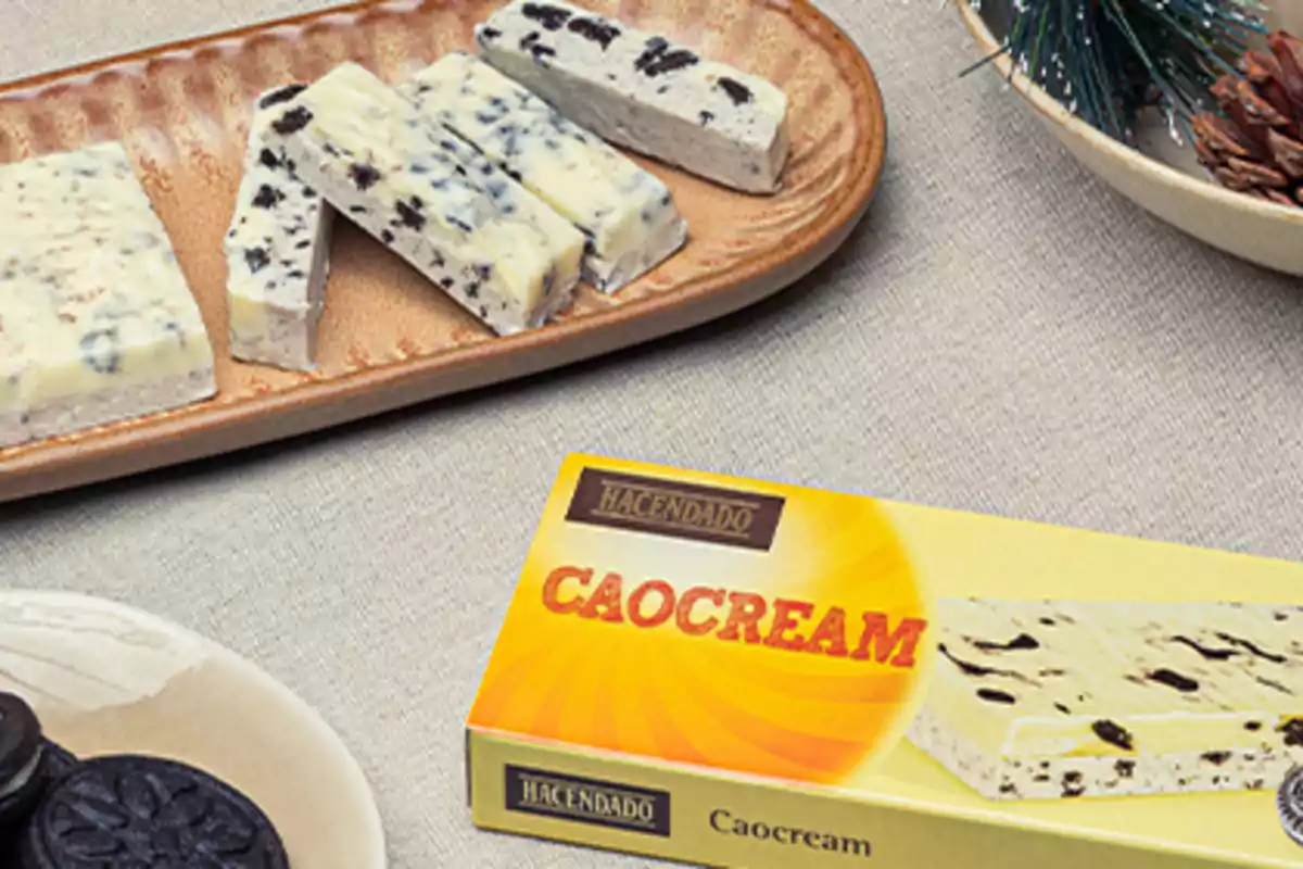 Turrón de chocolate blanco con galleta tipo oreo en una bandeja junto a su caja de la marca Hacendado sobre una mesa