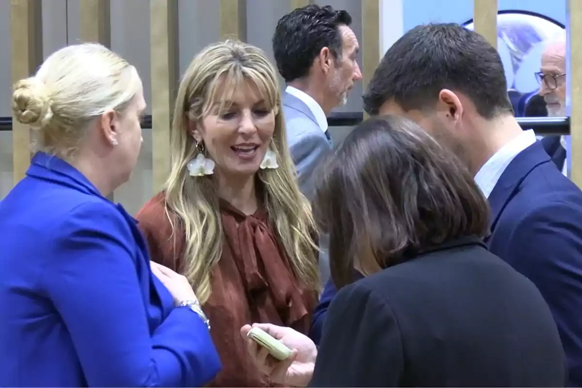 Varias personas conversan en un ambiente profesional mientras una de ellas sostiene un teléfono móvil