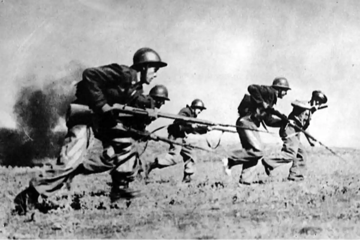 Soldados avanzan en formación con rifles y bayonetas en un campo durante una batalla