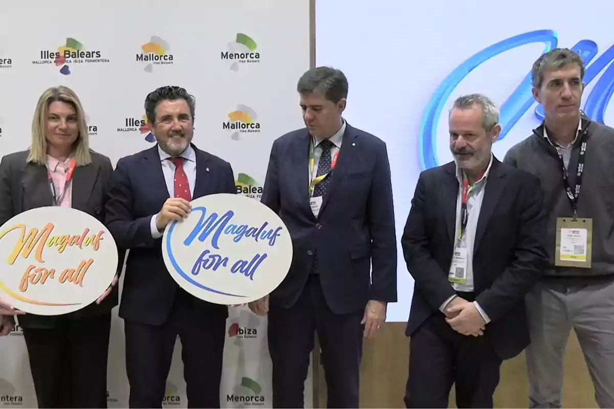 Cinco personas posan en un evento promocional sosteniendo carteles que dicen Magaluf for all con un fondo de logotipos de las Islas Baleares