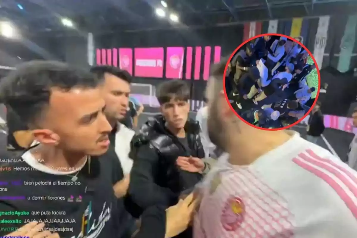 Un grupo de personas discute en lo que parece ser un evento deportivo bajo techo, con una pantalla rosa de fondo y un círculo rojo que resalta una vista aérea de más personas reunidas