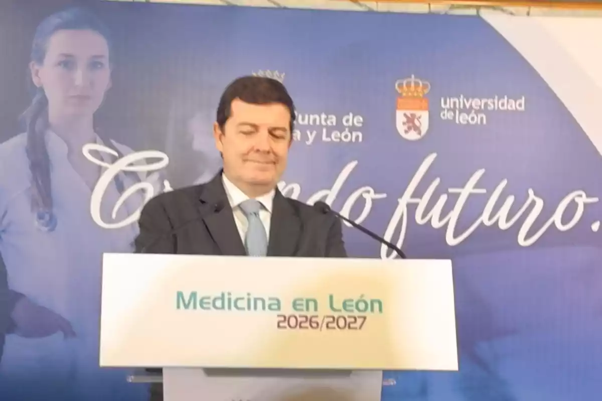 Hombre de traje hablando en un podio con el texto Medicina en León 2026 2027 y un fondo azul con logotipos de la Universidad de León y la Junta de Castilla y León