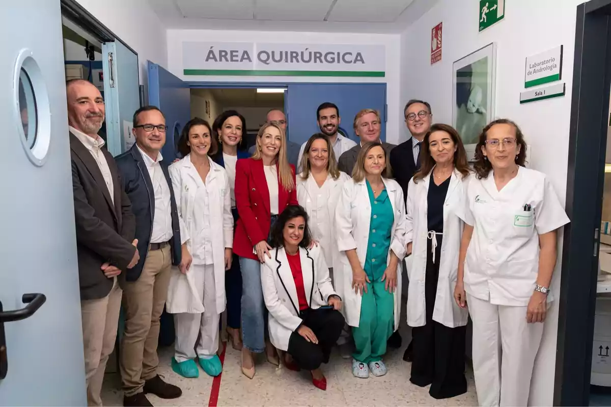 Un grupo de profesionales de la salud y otras personas posan sonrientes en la entrada de un área quirúrgica dentro de un hospital