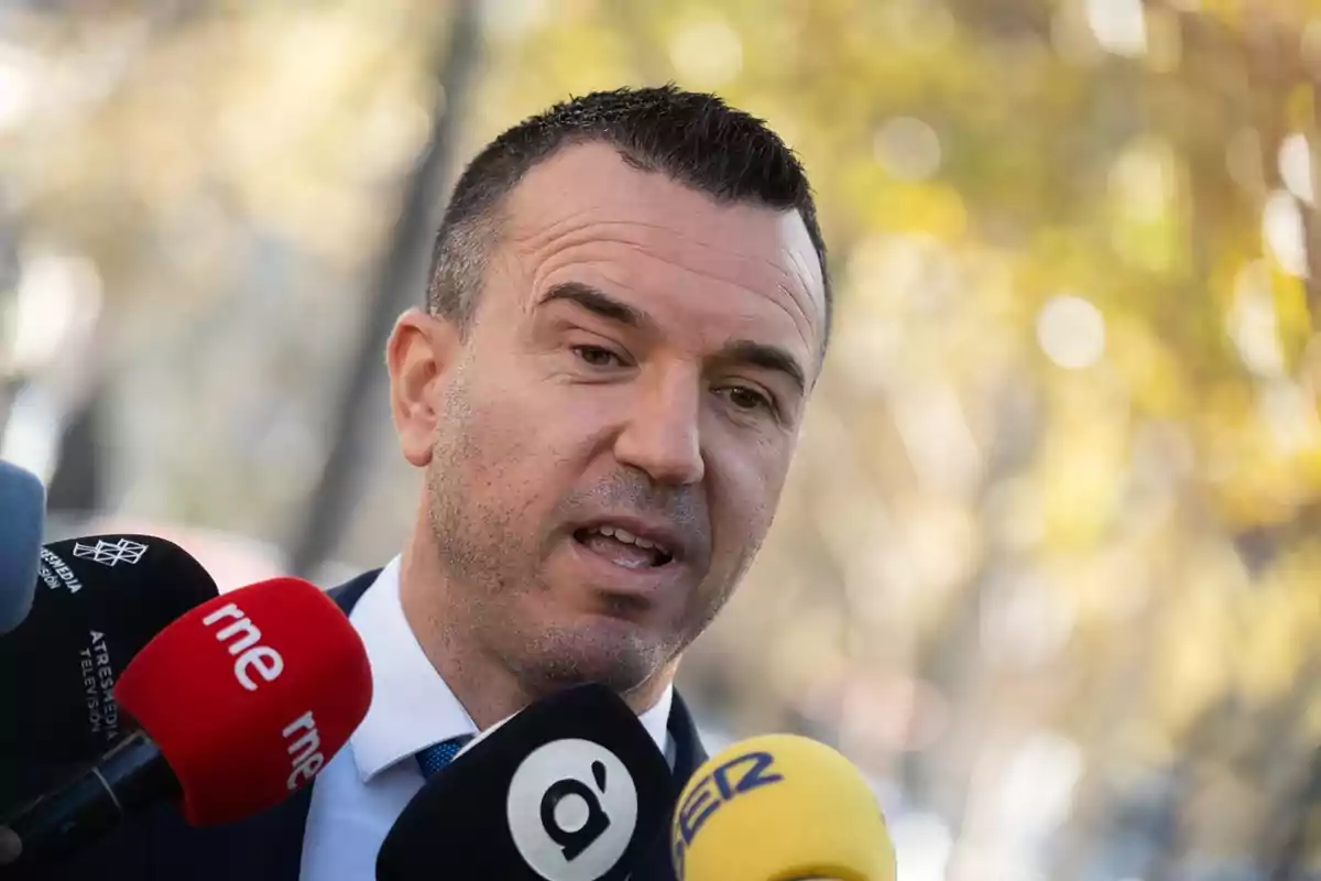 Hombre hablando frente a varios micrófonos de diferentes medios de comunicación al aire libre Hombre hablando frente a varios micrófonos de diferentes medios de comunicación al aire libre