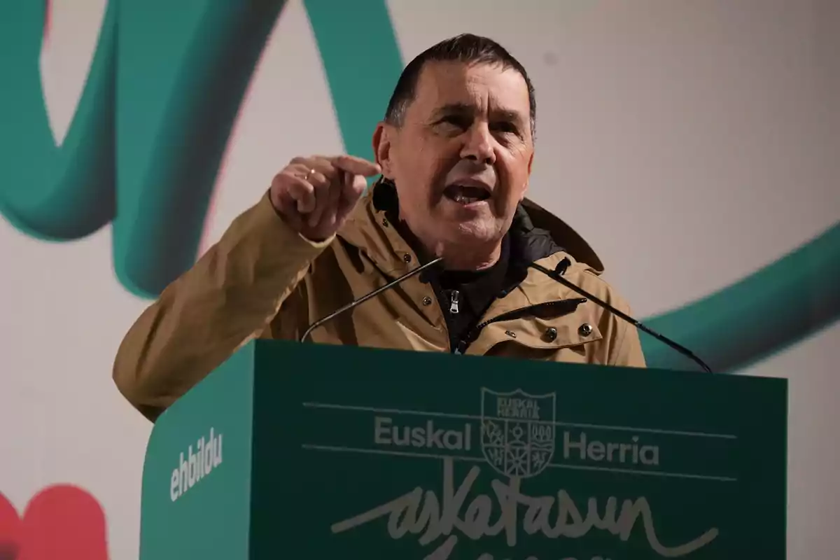 Hombre hablando en un mitin político detrás de un atril verde con el logo de EH Bildu