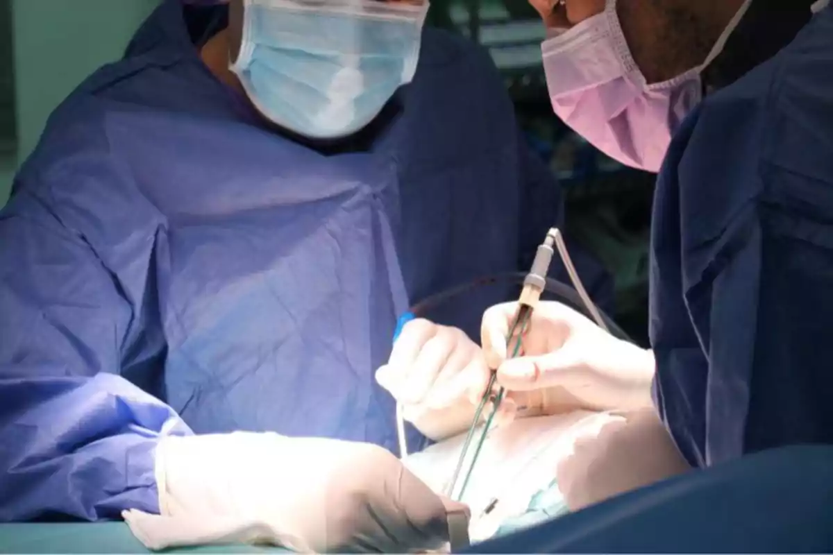 Dos cirujanos con mascarilla y guantes realizando una operación en un quirófano