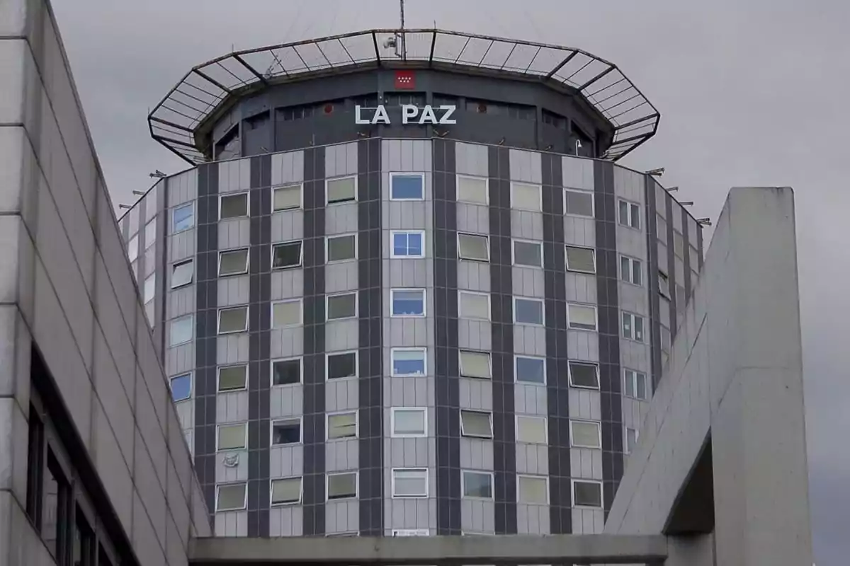 Edificio circular de varios pisos con ventanas rectangulares y el letrero La Paz en la parte superior bajo un cielo nublado Edificio circular de varios pisos con ventanas rectangulares y el letrero La Paz en la parte superior bajo un cielo nublado