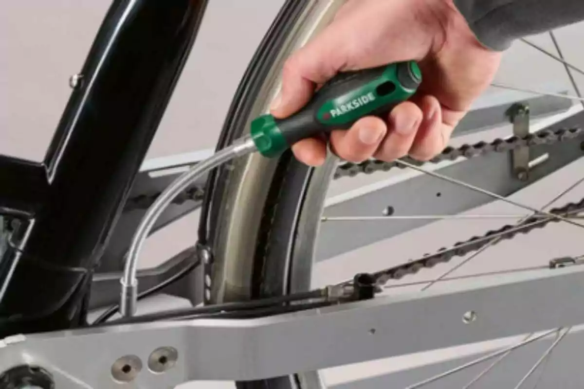 Persona usando un destornillador de Lidl para arreglar la llanta trasera de una bicicleta.