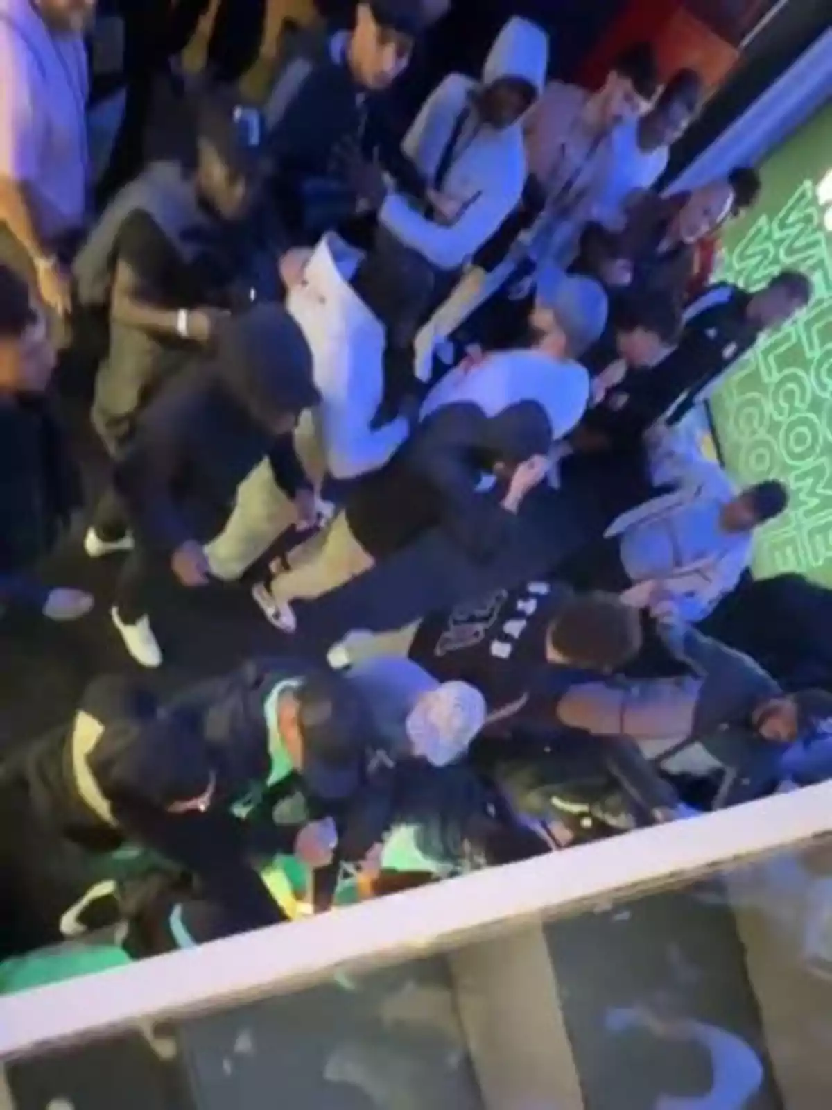 Grupo de personas reunidas en un espacio cerrado con iluminación colorida y un letrero de bienvenida al fondo