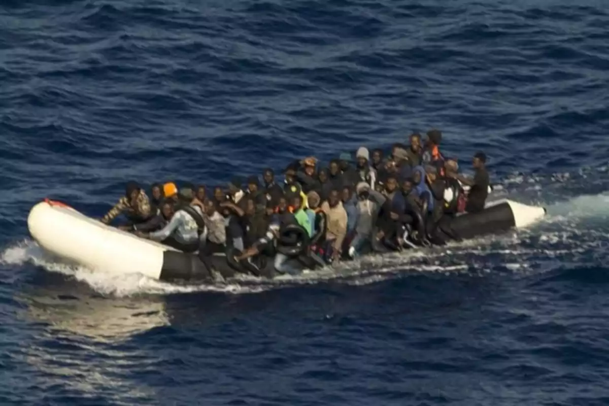 Un grupo numeroso de personas viaja en una balsa inflable sobre el mar