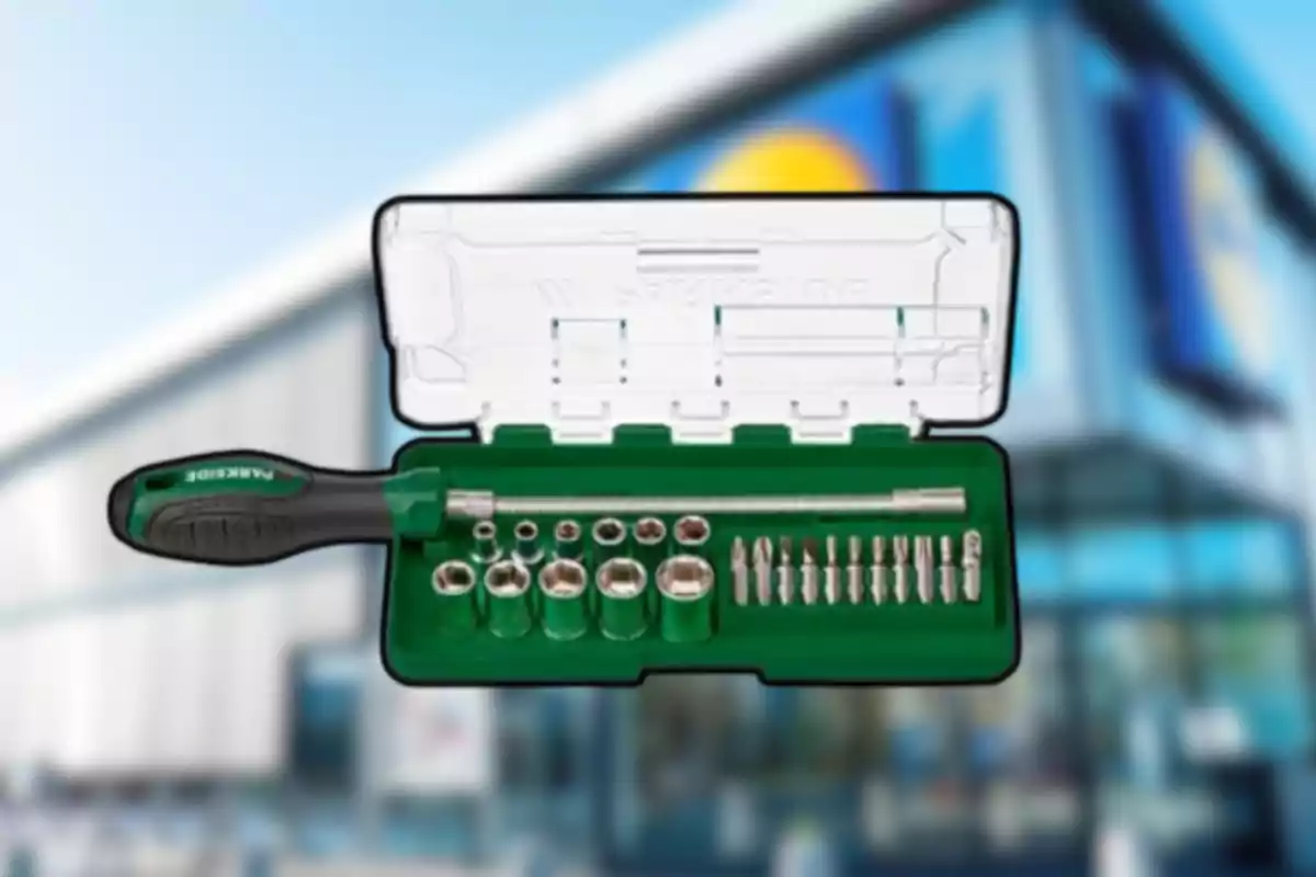 Estuche verde con destornillador y puntas metálicas frente a un edificio desenfocado
