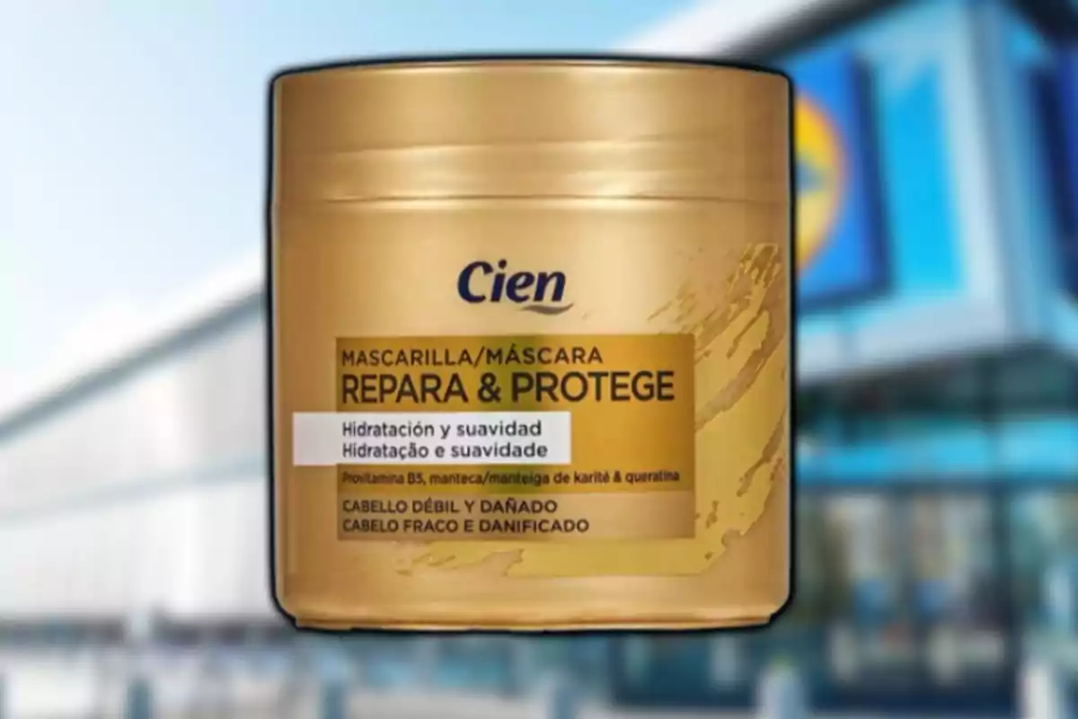 Envase dorado de mascarilla capilar Cien Repara & Protege para cabello débil y dañado con fondo de una tienda desenfocada
