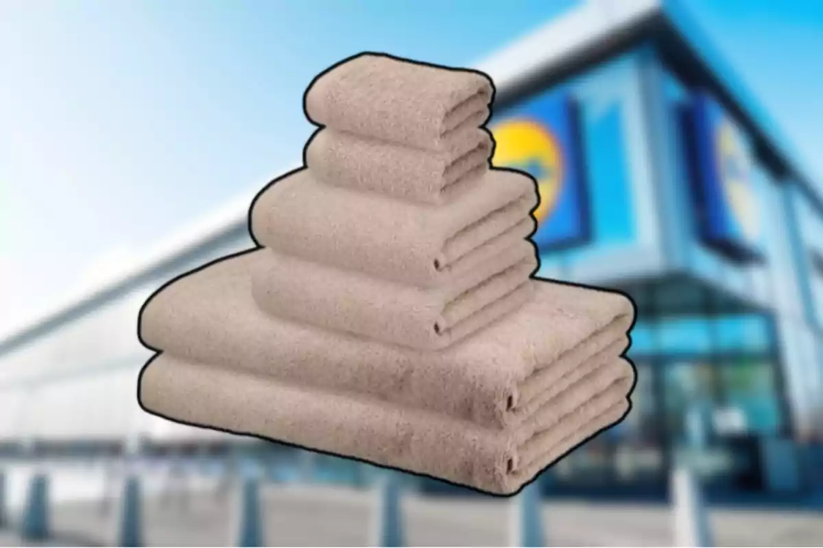 Un juego de toallas beige apiladas frente a una tienda con fachada moderna desenfocada