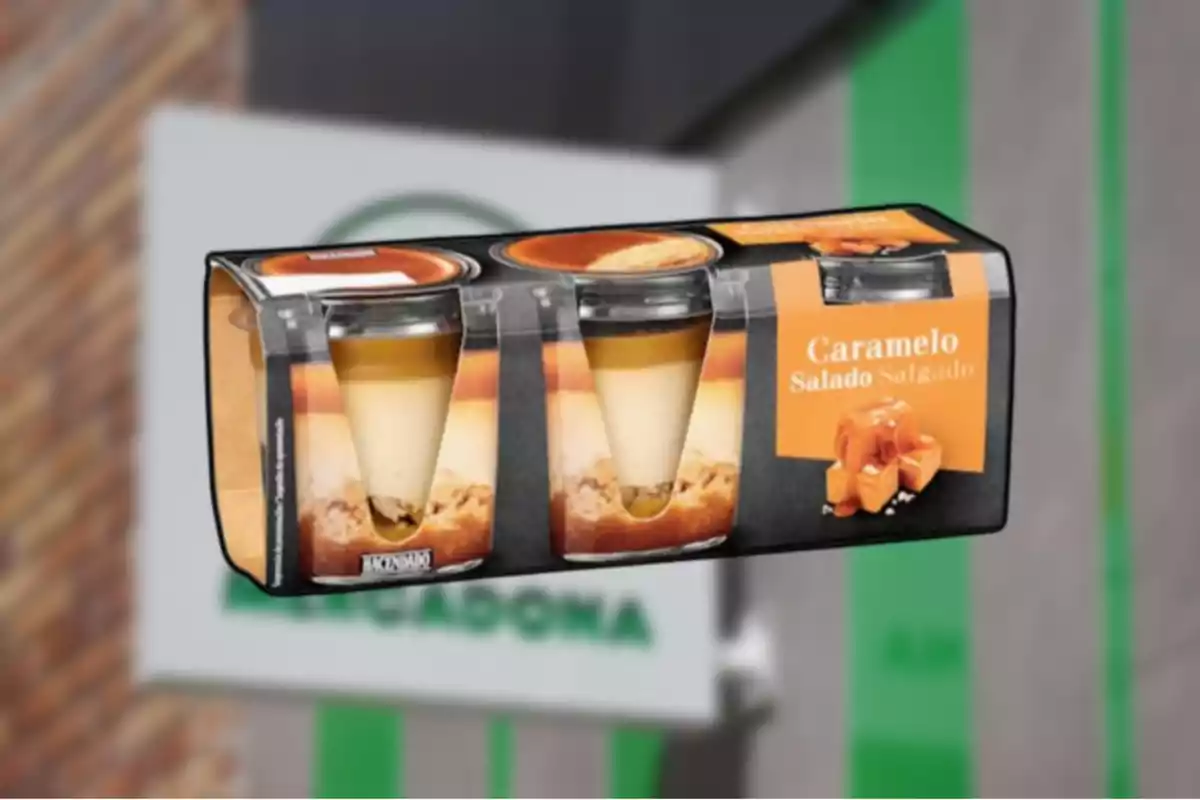 Postre de caramelo salado de la marca Hacendado en un envase de cuatro unidades frente a una tienda Mercadona desenfocada Postre de caramelo salado de la marca Hacendado en un envase de cuatro unidades frente a una tienda Mercadona desenfocada
