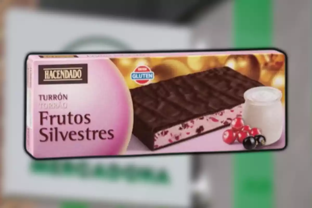 Caja de turrón de frutos silvestres de la marca Hacendado con cobertura de chocolate y un vaso de yogur junto a frutas rojas en la esquina