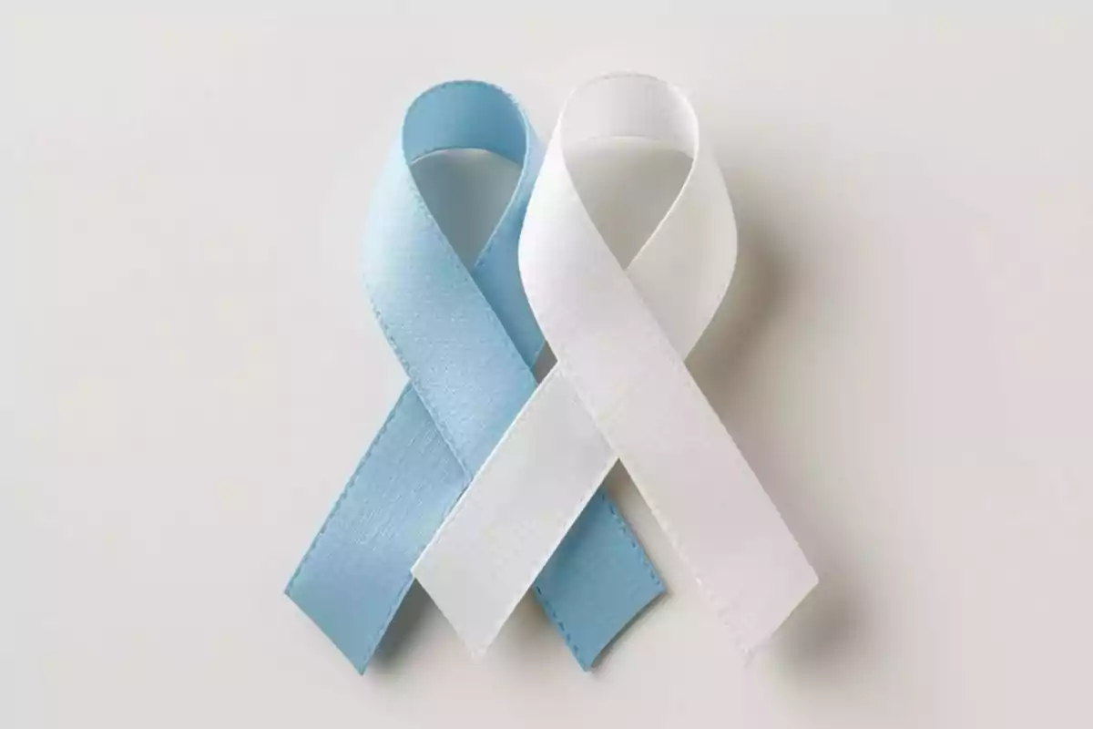 Dos listones en forma de lazo, uno azul claro y otro blanco, entrelazados sobre un fondo claro