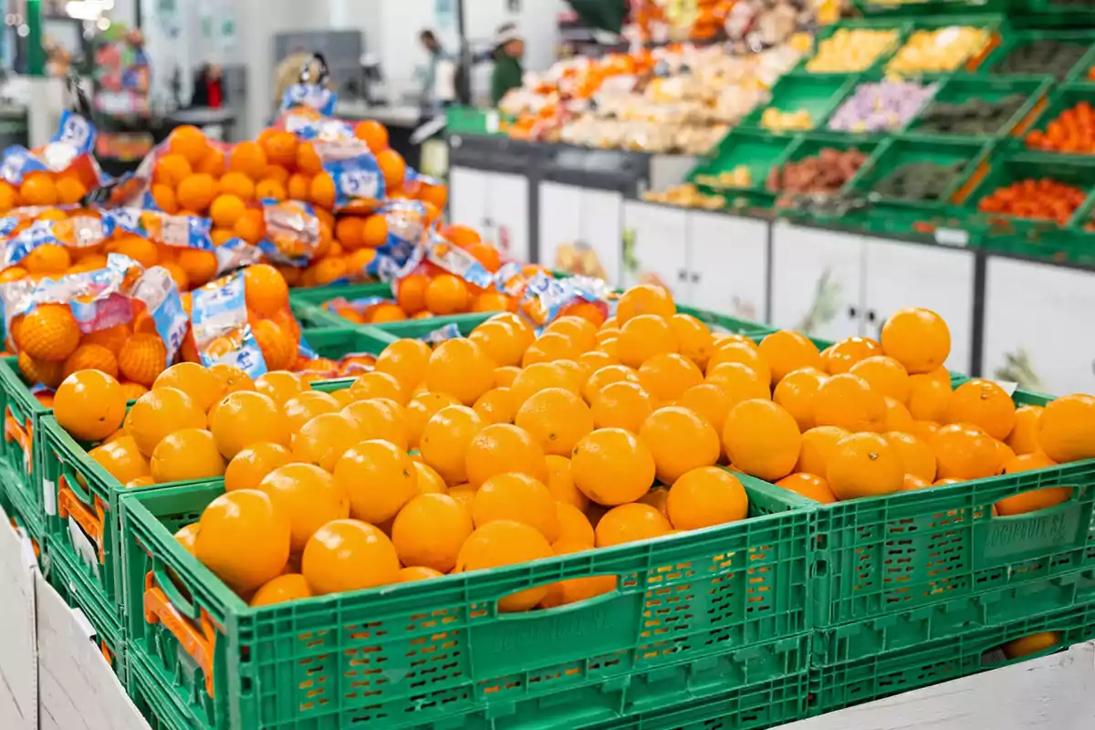 Naranjas frescas acomodadas en cajas verdes dentro de un supermercado