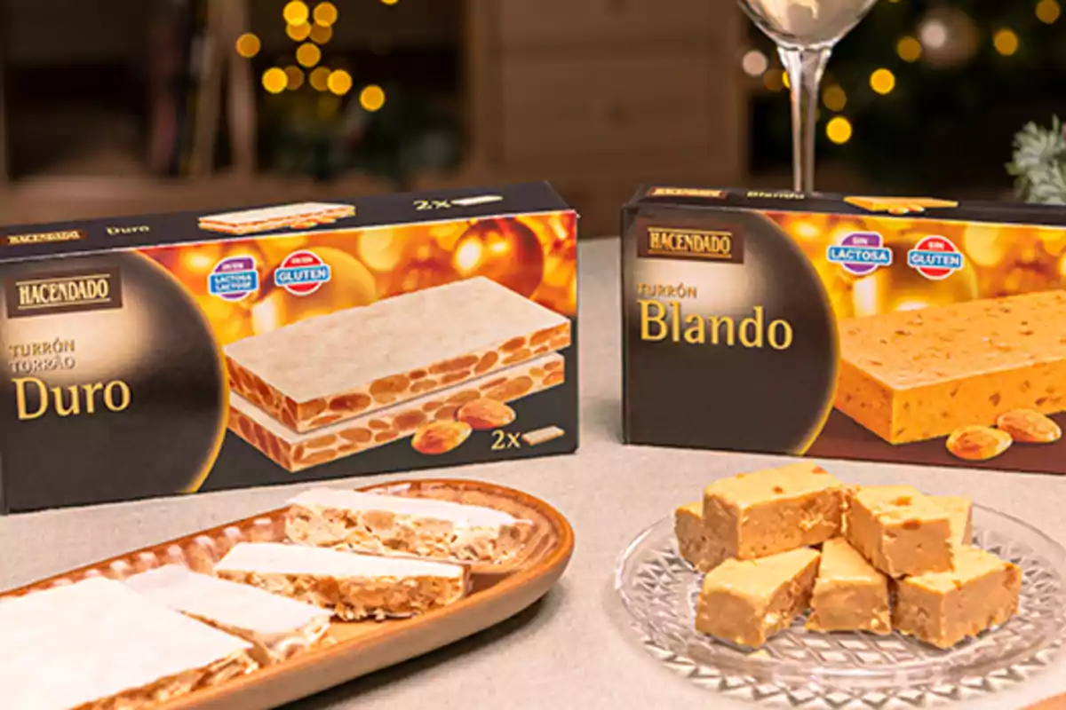 Cajas de turrón duro y blando de la marca Hacendado junto a platos con porciones de ambos tipos de turrón sobre una mesa