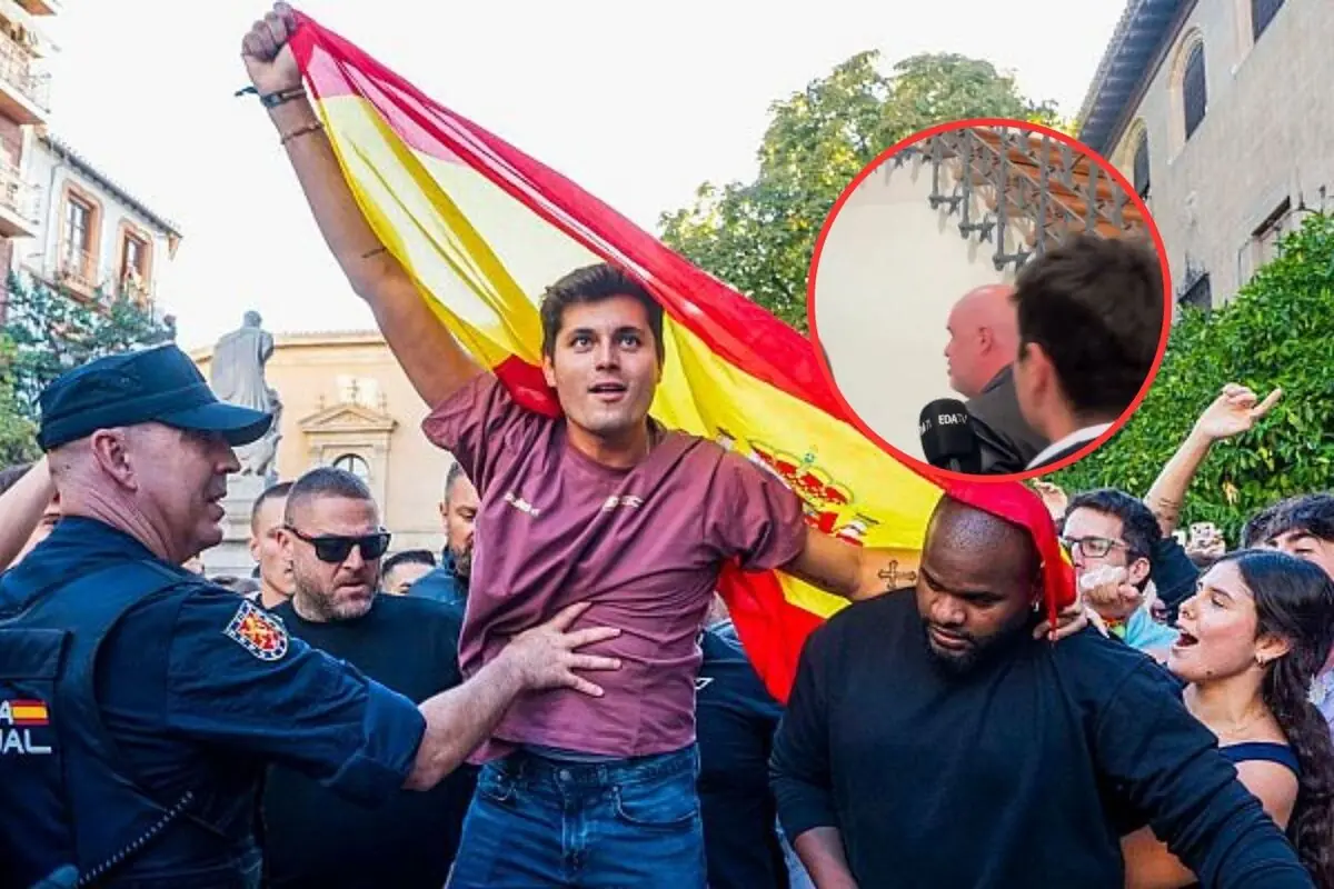 Un joven sostiene una bandera de España mientras es rodeado por varias personas y un policía, en un ambiente de manifestación, con un recuadro en la esquina superior derecha que muestra a dos hombres conversando en un interior.
