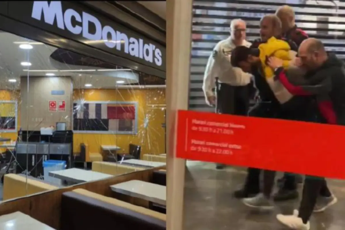 Interior de un McDonald’s con cristales rotos junto a varias personas reduciendo a un hombre en la entrada del local