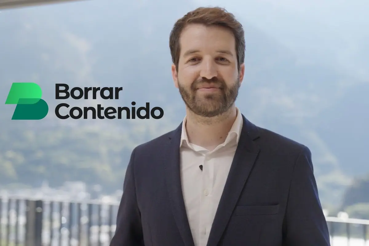 Hombre con barba y saco azul posando frente a un fondo de paisaje montañoso con el texto Borrar Contenido y un logotipo verde a la izquierda