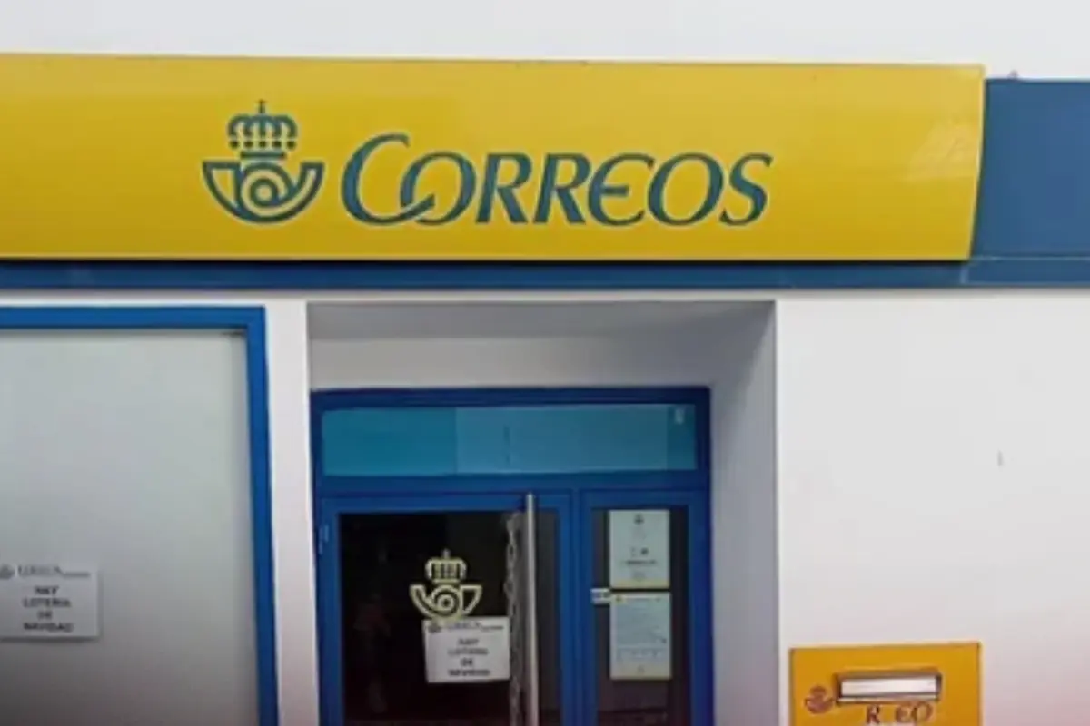 Fachada de una oficina de Correos de España con rótulo amarillo y azul y buzón amarillo en la pared