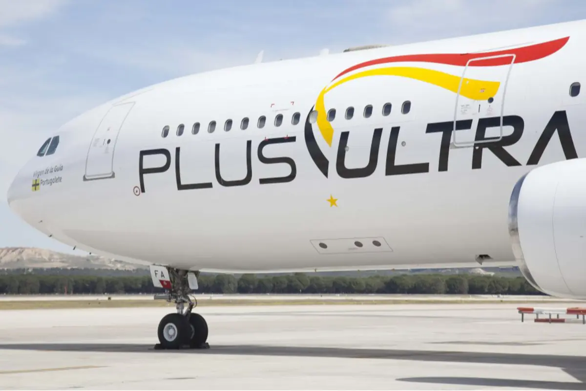 Avión de la aerolínea Plus Ultra estacionado en la pista con el logotipo visible en el fuselaje blanco