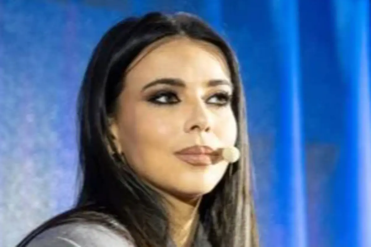 Mujer de cabello oscuro usando micrófono de diadema frente a fondo azul