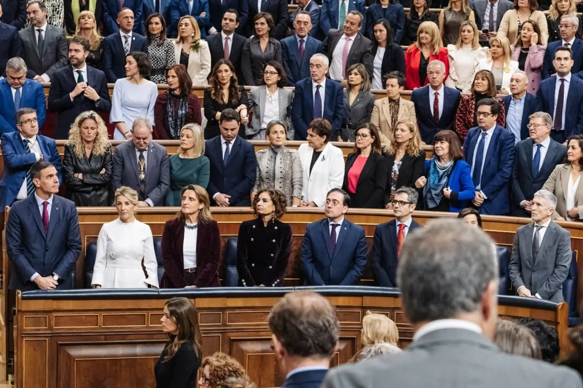 Un grupo numeroso de personas vestidas de manera formal se encuentra reunido en un recinto parlamentario