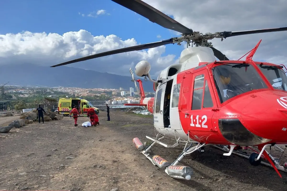 Helicóptero de emergencias y ambulancia en una operación de rescate con personal sanitario atendiendo a una persona en un terreno al aire libre