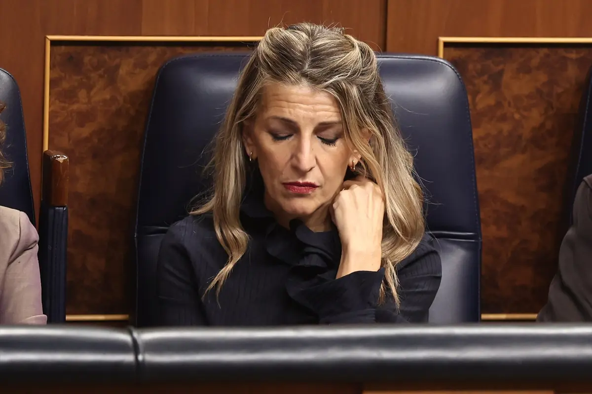 Mujer sentada en un sillón azul con los ojos cerrados y expresión seria