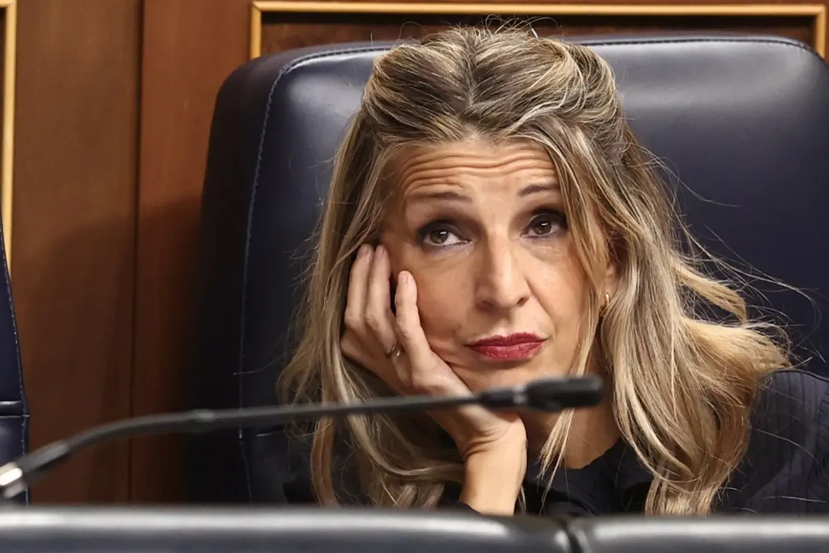 Mujer sentada con expresión pensativa apoyando la cabeza en la mano en una sala de reuniones