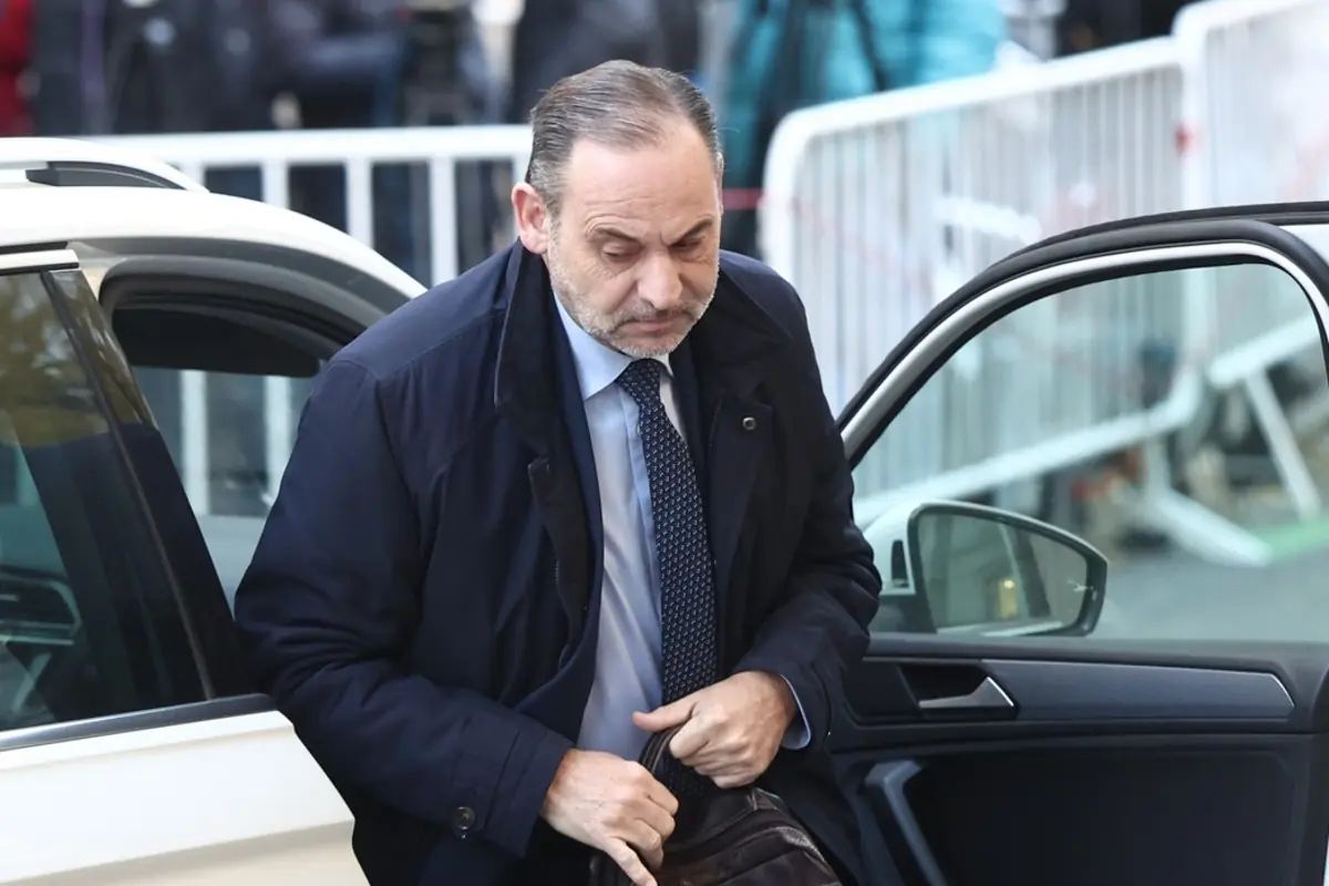 Hombre de mediana edad con saco azul saliendo de un automóvil blanco mientras sostiene un maletín