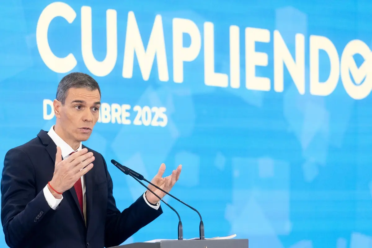Hombre de traje hablando en un podio frente a un fondo azul con la palabra cumpliendo y la fecha diciembre 2025