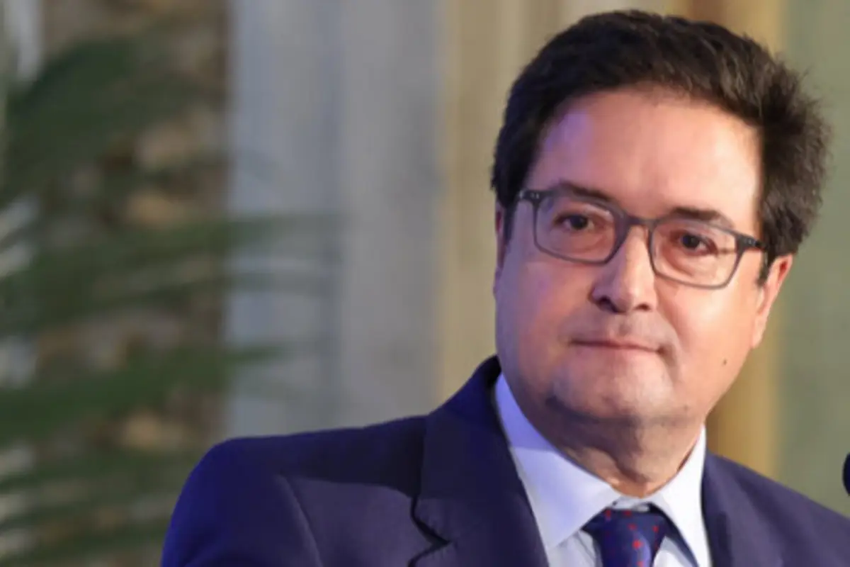 Hombre de mediana edad con gafas y traje azul mirando hacia un lado en un entorno interior profesional