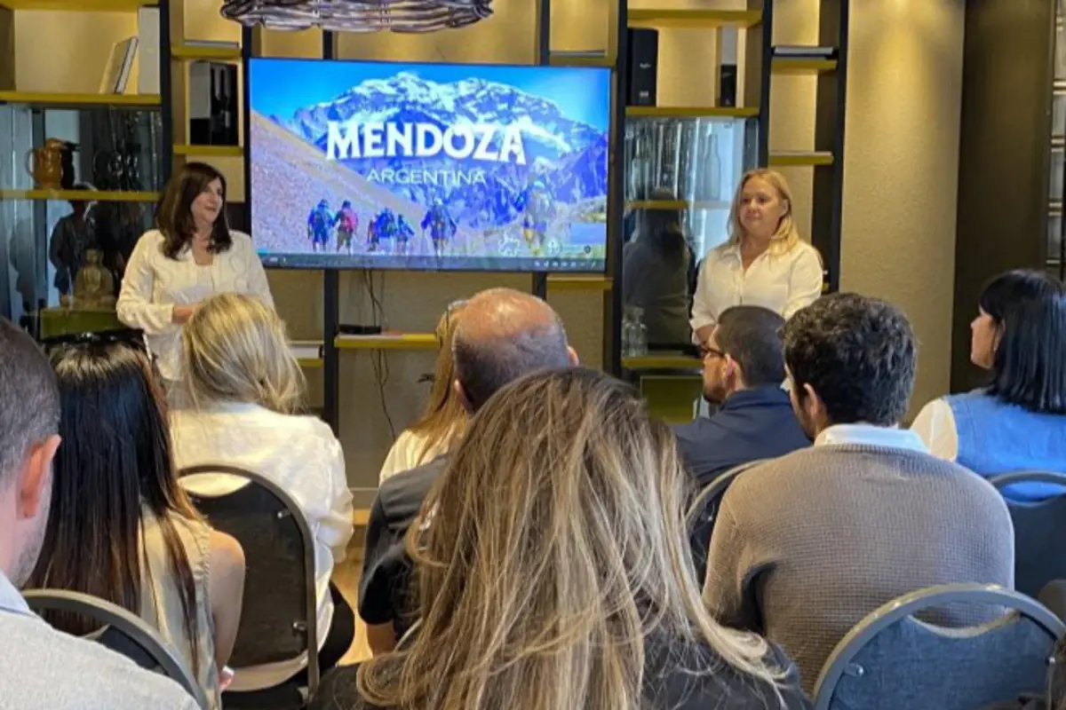 Personas sentadas escuchando una presentación sobre Mendoza Argentina con una pantalla que muestra una imagen de montañas y excursionistas