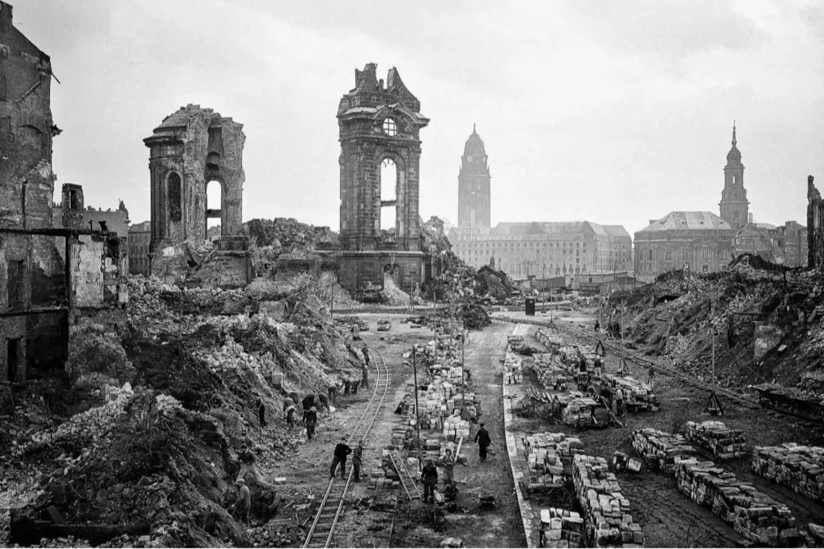 Ciudad devastada con edificios en ruinas y personas trabajando entre escombros