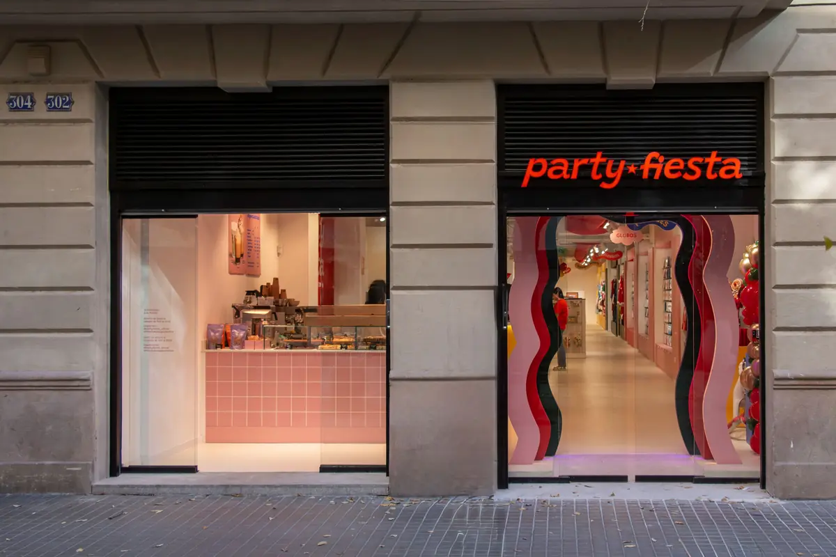 Fachada de una tienda llamada party fiesta con entrada decorada y escaparate de productos a la izquierda