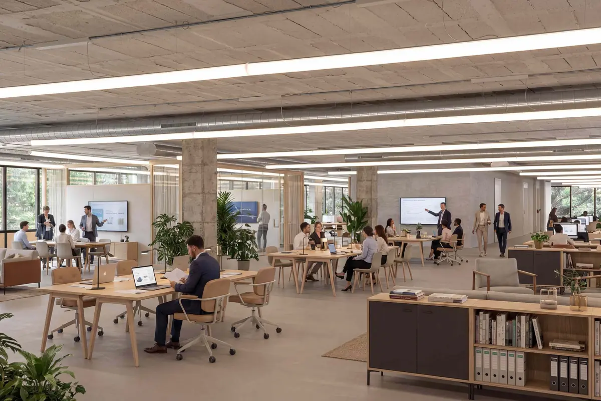 Oficina moderna y espaciosa con varias personas trabajando y colaborando en diferentes áreas, rodeadas de plantas y luz natural