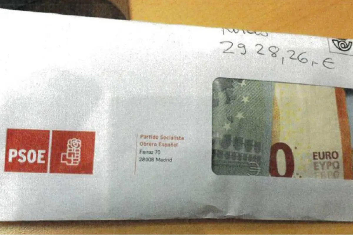 Sobre blanco del PSOE con ventanilla transparente donde se ve un billete de cero euros y anotaciones manuscritas en la parte superior Sobre blanco del PSOE con ventanilla transparente donde se ve un billete de cero euros y anotaciones manuscritas en la parte superior