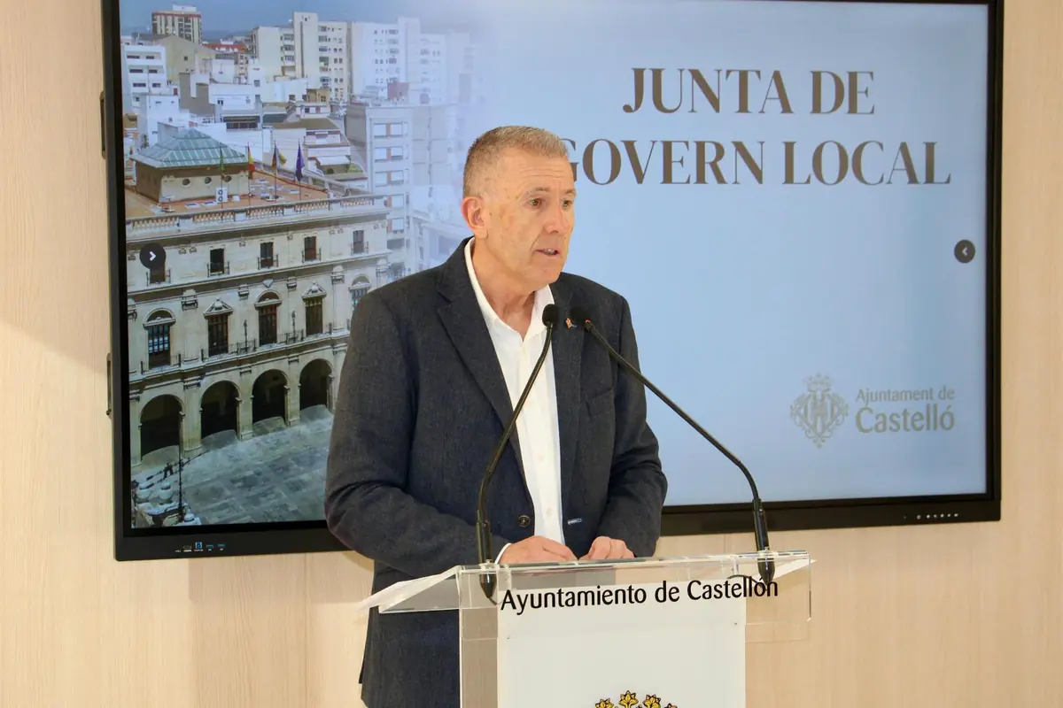 Hombre de mediana edad hablando en una rueda de prensa en el Ayuntamiento de Castellón frente a un atril con micrófonos y una pantalla que muestra el texto Junta de Govern Local