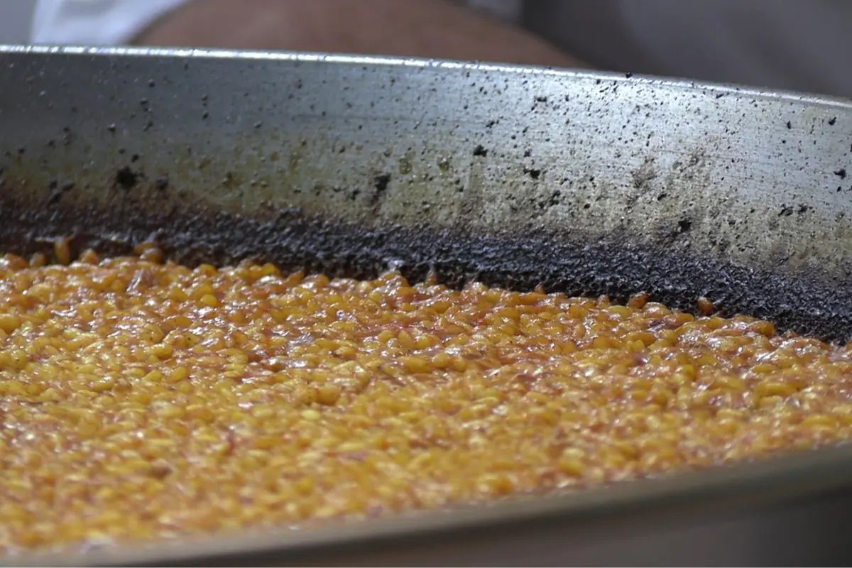 Granos de maíz caramelizados cocinándose en una sartén grande de metal